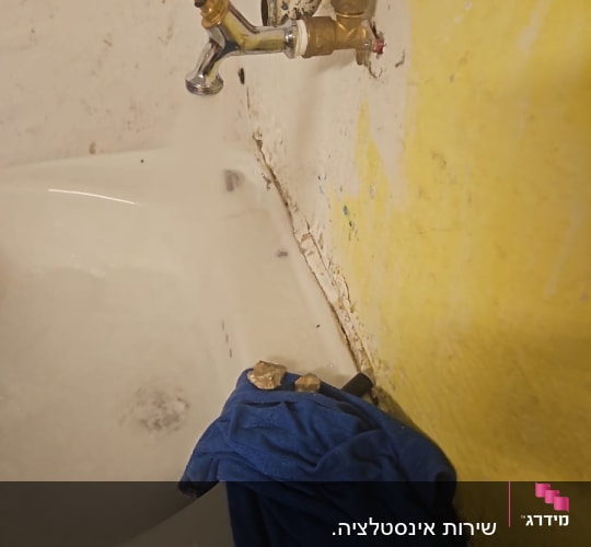 ברז וכיור עם צינורות, מגבת כחולה על הכיור